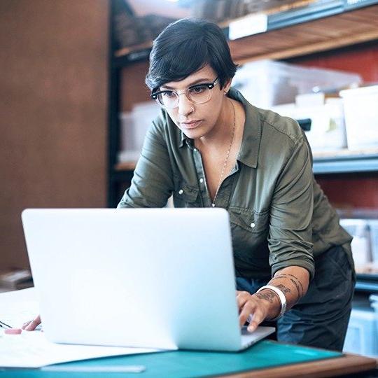 一个穿绿色衬衫的黑发女人在储藏室里拿着笔记本电脑